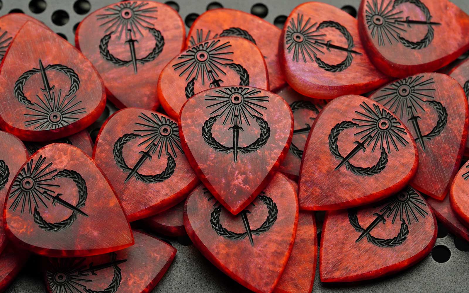 Limited Sol Invictus 5mm red resin guitar picks with black-filled solar sword and laurel engravings