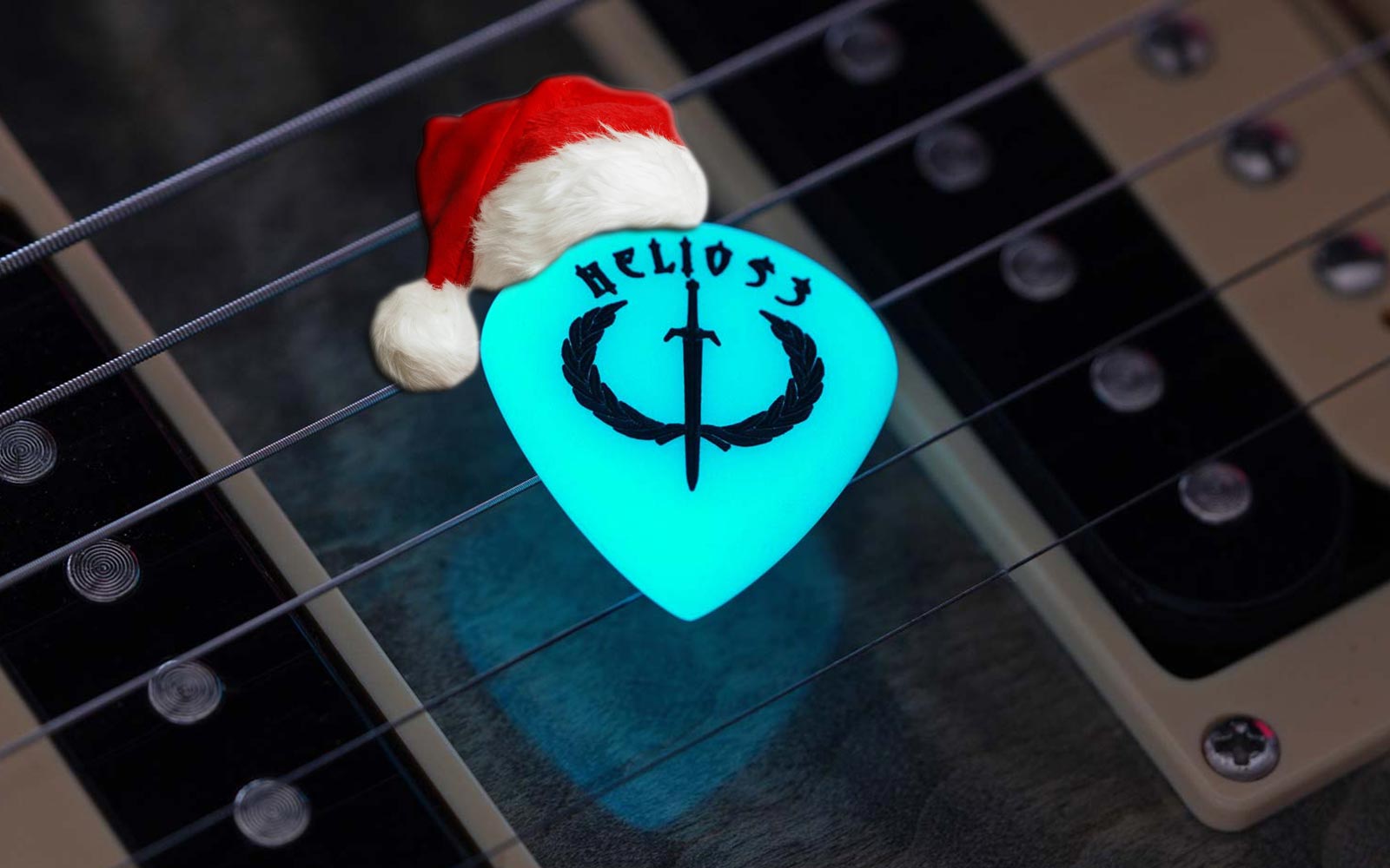Helios-3 glow-in-the-dark guitar pick wearing a Santa hat.