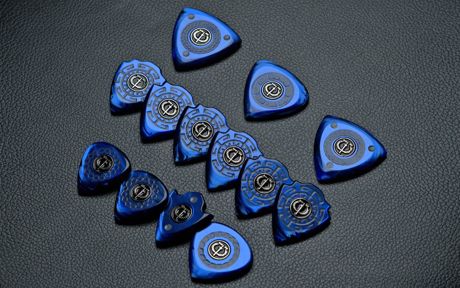 Imperial Collection guitar picks—blue pearlescent acrylic with sword-and-laurel emblems on black leather.