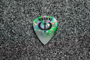 Glowing guitar pick with intricate design on a textured black surface