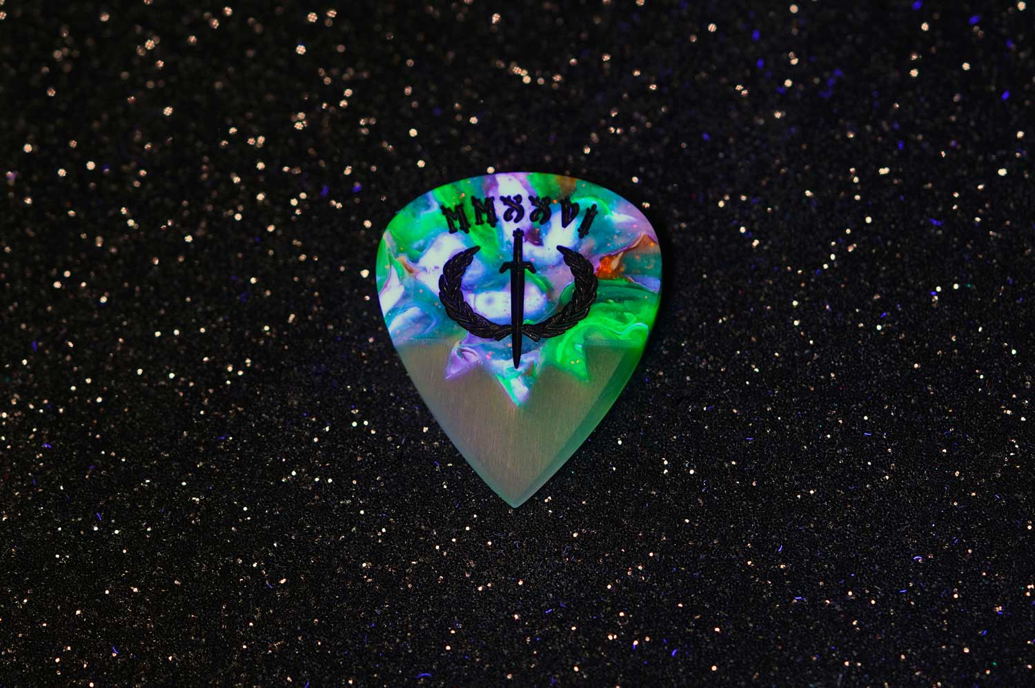 Glowing guitar pick with intricate design on a textured black surface